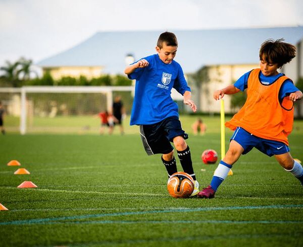 6-year-old boy practicing dribbling around cones using both feet during a football drill