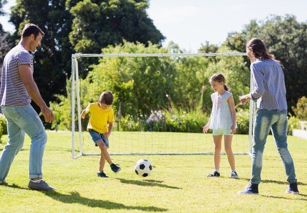 Father playing football in the backyard with his young child as part of home training